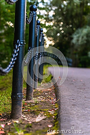 Colorful Photo of the Road in a Park, Between Woods - Closeup view of the Chain Fence with Blurred Background with Space for Text Stock Photo