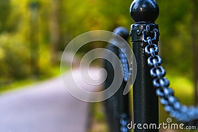 Colorful Photo of the Road in a Park, Between Woods - Closeup view of the Chain Fence with Blurred Background with Space for Text Stock Photo