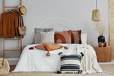 pillows on white bed of classy bedroom with round wooden bedside table and ladder Stock Photo