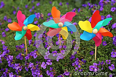 Colorful pinwheel toys between blue flowers Stock Photo