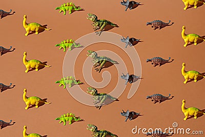 Colorful plastic dinosaur toys on a brown background. Pattern Stock Photo