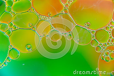 Colorful plastic oil bubbles on water surface with green, yellow, orange and red colours Stock Photo