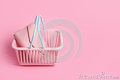 Colorful plastic shopping basket with leather wallet. Empty pink and blue supermarket basket on pink pastel background. Creative Stock Photo