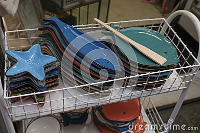 Colorful plates of fish shapes selling on the market close-up. Tableware on shelves Stock Photo