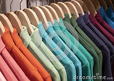 Colorful polo shirt on hang for sale in shop. Green blue polo on wooden hanger. Summer season wear in department store Stock Photo