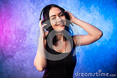 Colorful portrait in blue and pink ligth of a young DJ woman wearing headset and enjoying an electronic music. Stock Photo