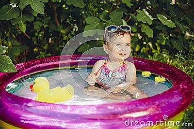 Colorful portrait of cheerful baby enjoying her day in little pool Stock Photo