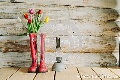 Colorful rain boots with spring flowers and oli lamp in wooden b Stock Photo