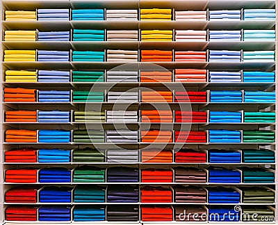 Colorful rainbow clothes background .Various vibrant color shirts perfectly folded on a shelf in the shop. Colored male Stock Photo