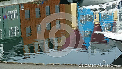 Colorful reflection in harbour water, houses, brown facade center, sailboat lower right Stock Photo