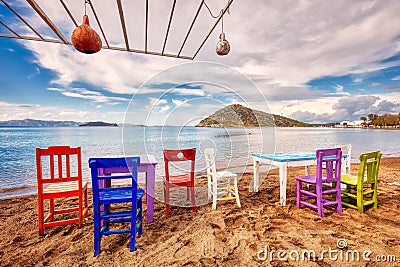 Colorful retro wooden chairs and a table lined up on the beach at the seaside Stock Photo