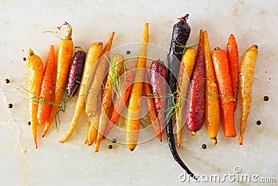 Colorful roasted rainbow carrots arranged in a row over a white marble background Stock Photo