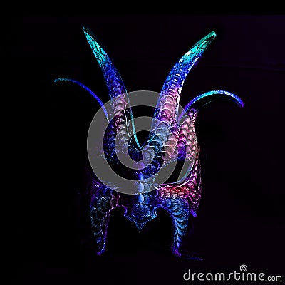 A colorful, scary halloween mask in blues and purples against a black background. Stock Photo