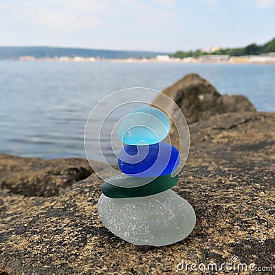 Colorful seaglass stack on beach rock with seascape background. Beachcombing Stock Photo