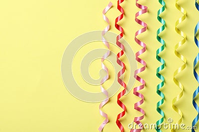Colorful serpentine streamers on yellow background, flat lay. Space for text Stock Photo