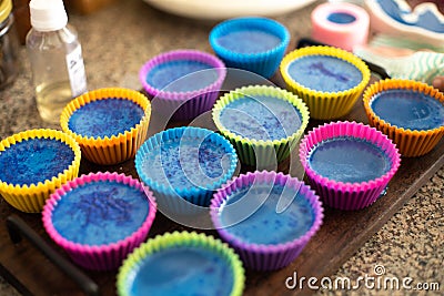 Colorful silicon cupcake molds on wooden coard filled with liquid soap for a home made hobby of melt and pour soapmaking Stock Photo