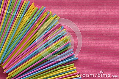 Colorful single use disposable plastic straws in the corner on the pink surface. Stock Photo