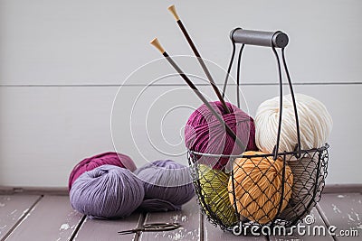 Colorful spring wool yarn in an iron basket with wooden knitting needles Stock Photo