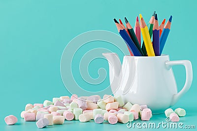 Colorful stationery in white kettle on aquamarine background Stock Photo