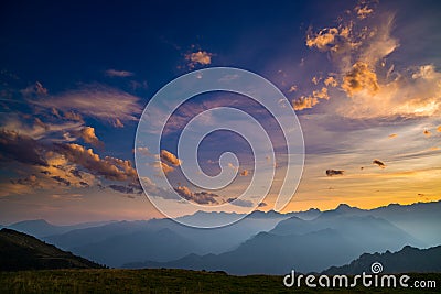 Colorful sunlight on the majestic mountain peaks, green pastures and foggy valleys of the Italian Alps. Golden cloudscape at sunse Stock Photo