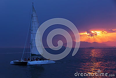 Colorful sunset. Dramatic and Atmospheric landscape. Costa Brava, Spain. Seacoast. Seascape with sailboat. Tourist catamaran. Stock Photo