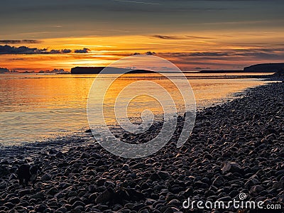 Colorful sunset over ocean, rough stone coast in foreground. Warm and cool color. Salthill beach, Galway city, Ireland. Selective Stock Photo