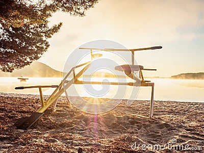 Colorful sunset with seesaw on beach. Teeter totter with wooden chairs Stock Photo