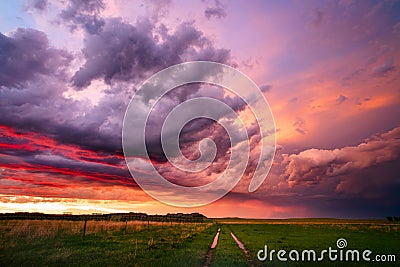Colorful sunset sky over a dirt road and field Stock Photo