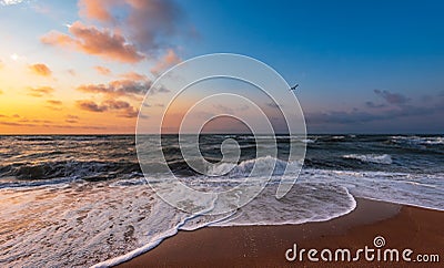 Colorful sunset with wave splashes on the beach Stock Photo