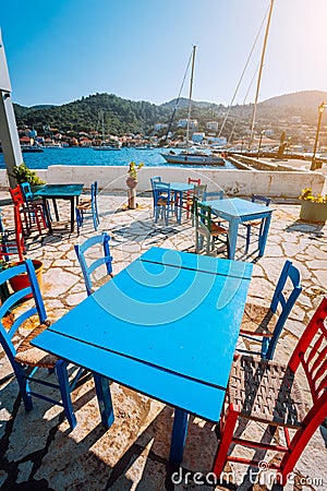 Colorful table and chairs in a typical tavern by the sea. Greek fishing village at hot summer day Stock Photo