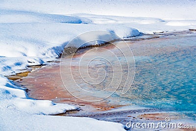 Colorful thermal pool surrounded by snow in Yellowstone in winter Stock Photo
