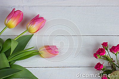 Colorful tulips with miniature roses on wooden table. Stock Photo