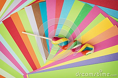 Colorful twisted sweet lollipop and brightly colored papers back Stock Photo