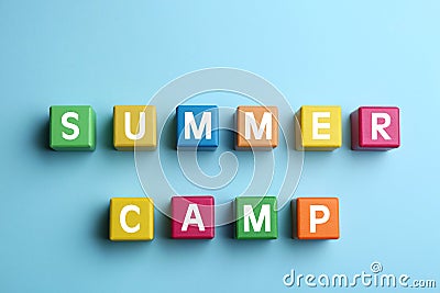 Colorful cubes with phrase SUMMER CAMP on light blue background, flat lay Stock Photo