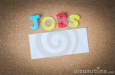 Colorful Wooden word JOBS with piece of White paper on cork board Stock Photo