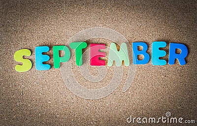 Colorful wooden word SEPTEMBER on cork board with selective focus Stock Photo