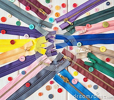 Colorful zippers and buttons on white wooden table. Rustic style. Needlework. Stock Photo