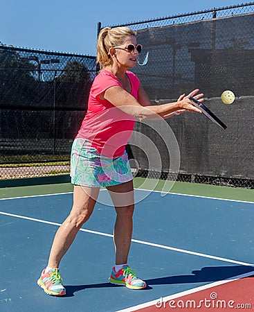 Colorfully dressed pickleball player with her eye on the ball Stock Photo