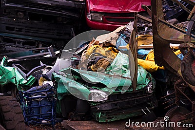 Colors on the junkyard, crushed turquoise scrap car, yellow garb Stock Photo