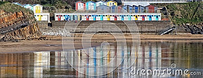 Coloured beach huts, reflected on the wet sand, Bude, Cornwall. Stock Photo