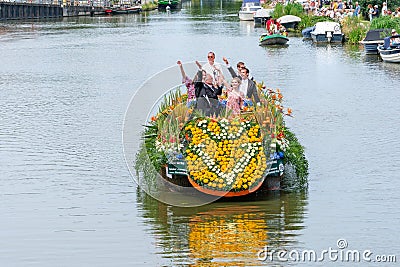 Colourful canal parade of flower and vegetables decorated boats with cheerful dressed up singing and dancing people Editorial Stock Photo