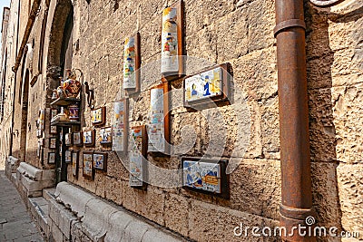 colourful ceramic images and jugs on outside wall in old Italian town of Gubbio Editorial Stock Photo