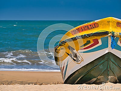 A colourful fishing boat pulled up on a tropical beach with blue water and sky behind. Editorial Stock Photo