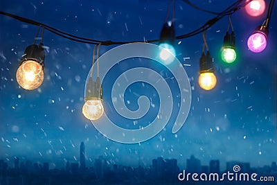 Colourful glowing christmas lights in snowfall on the dark blue city Stock Photo