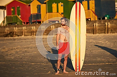 Colourful image of male surfer on beach with surfboard Stock Photo