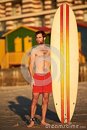 Colourful image of male surfer on beach with surfboard Stock Photo