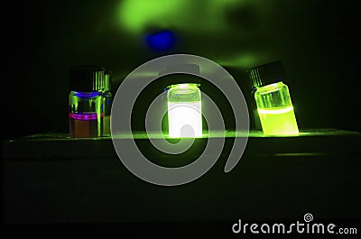 Colourful light induced catalyst photochemical reaction in glass vials under green light in a dark chemistry laboratory Stock Photo