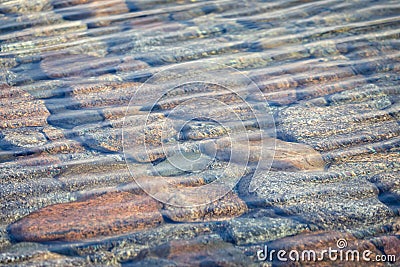 Colourful pebbles seen through crystal clear glacier melt water lake Stock Photo