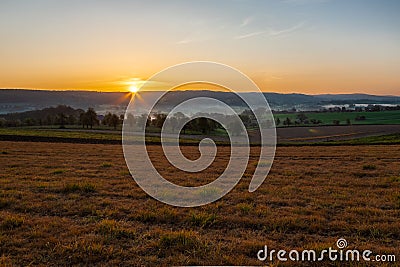 Colourful sunrise on a summer morning with a little fog on the ground and spectacular views over the Dutch hillside in Limburg Stock Photo