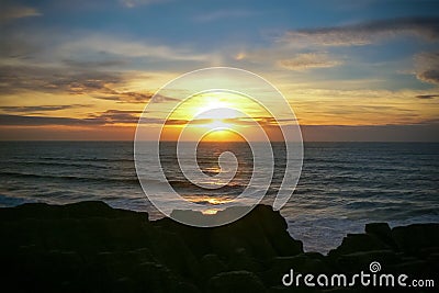 Colourful sunset over the sea at Punakaiki Pancake Rocks and Blowholes, New Zealand Stock Photo